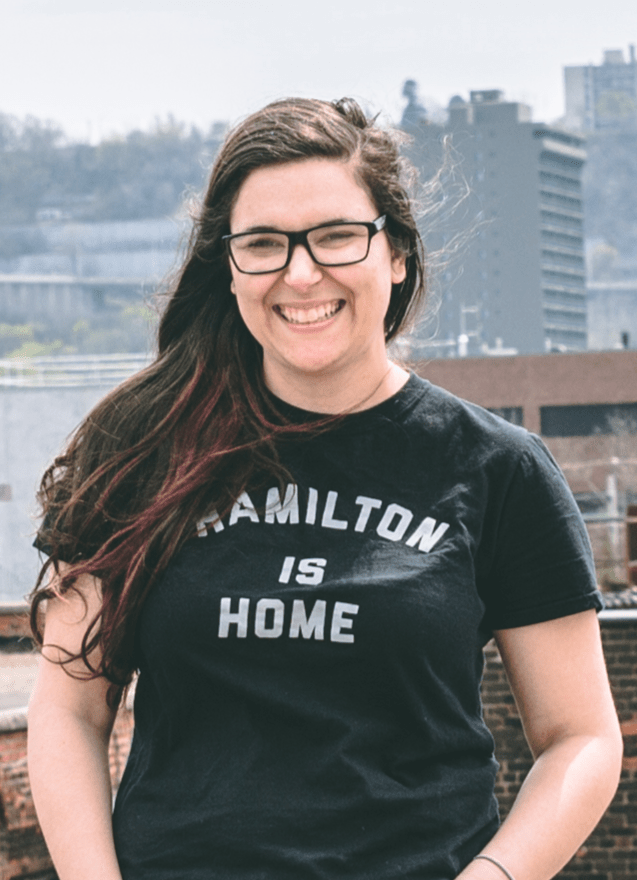 Photographer Christina Macaluso-Thomas smiling, wearing a t-shirt that says "Hamilton is Home".