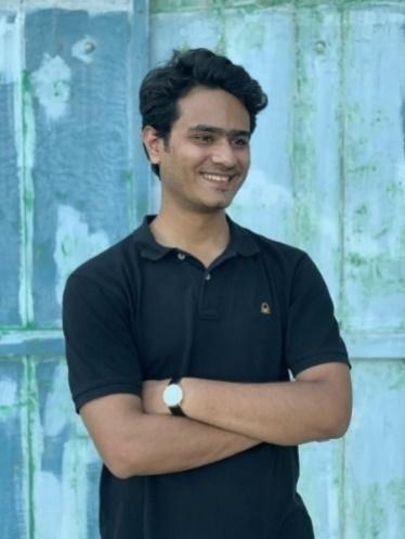 Photographer Sahil Ali smiling with arms folded in front of wall.