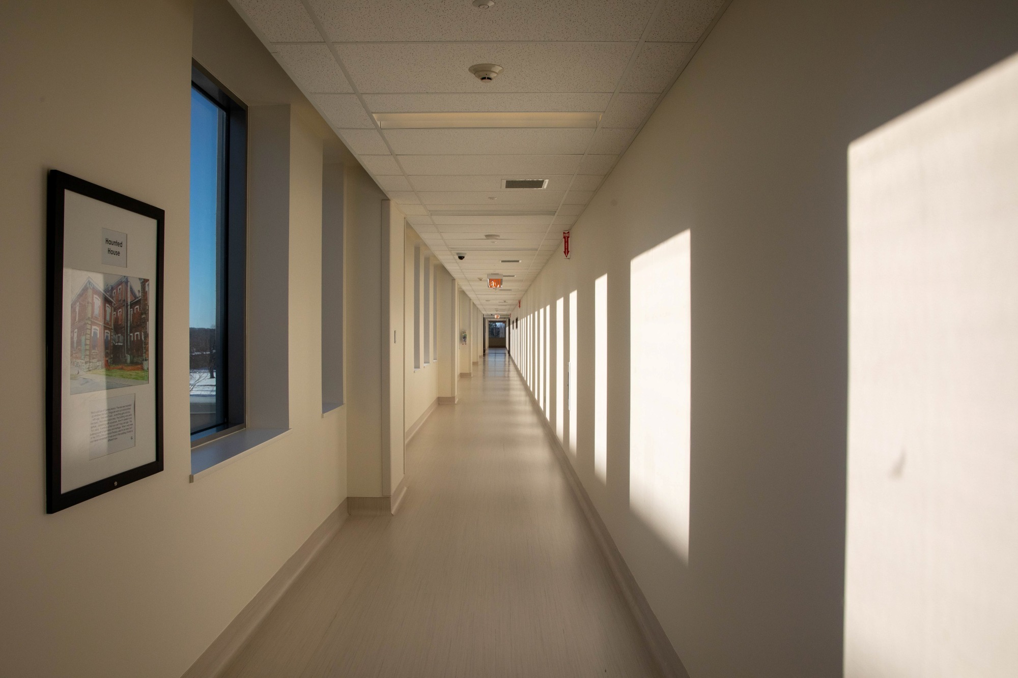 A long, empty, and brightly lit hallway with light-colored walls and flooring.